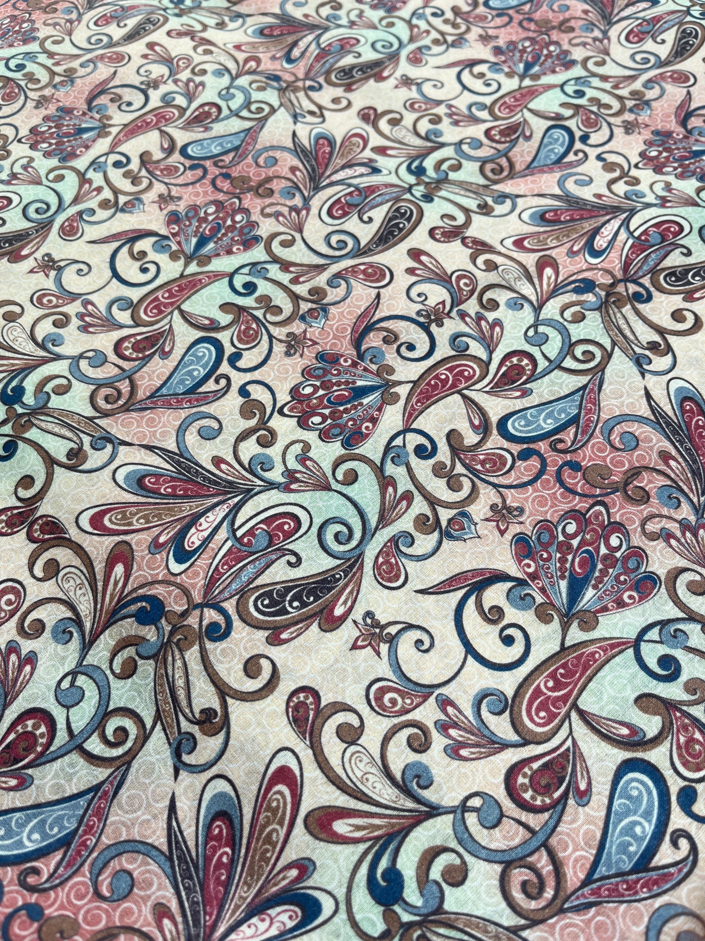 Patterned fabric with intricate designs in red, blue, and beige.