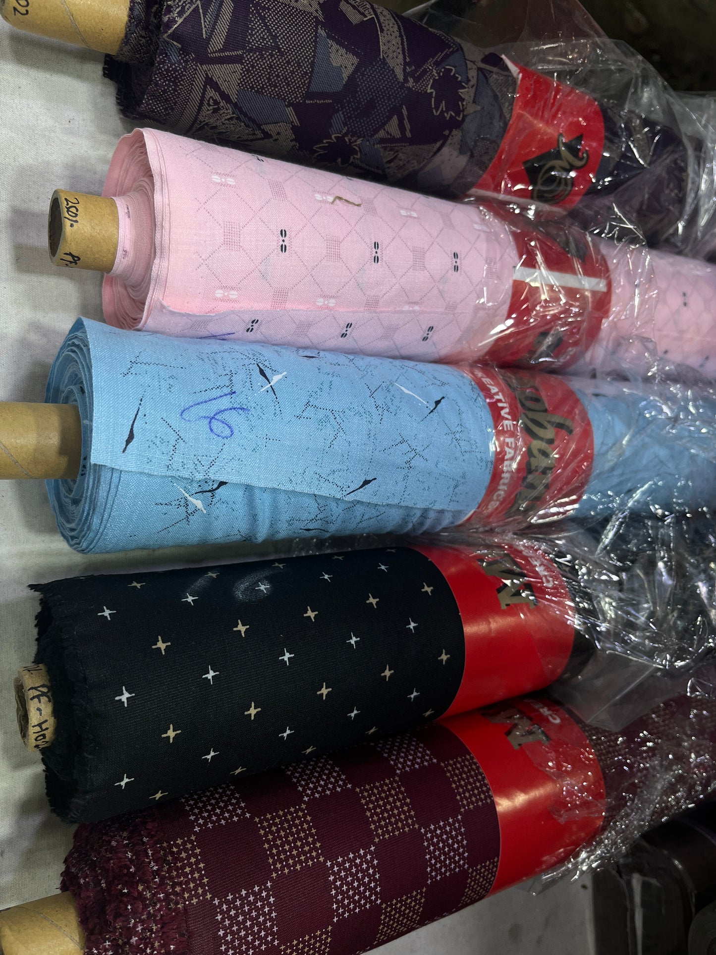 Rolls of fabric with various patterns and colors on a white surface.