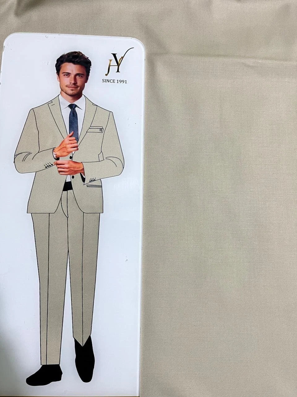 Card with a beige suit design and a man wearing the suit on a beige fabric background