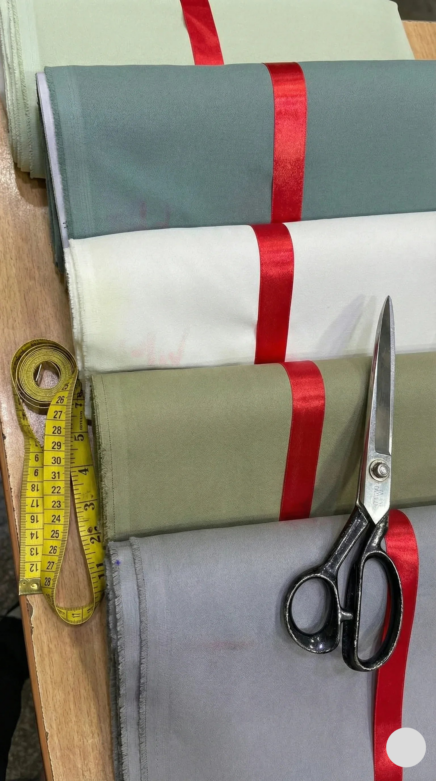 Fabric with red ribbon, scissors, and measuring tape on a wooden surface