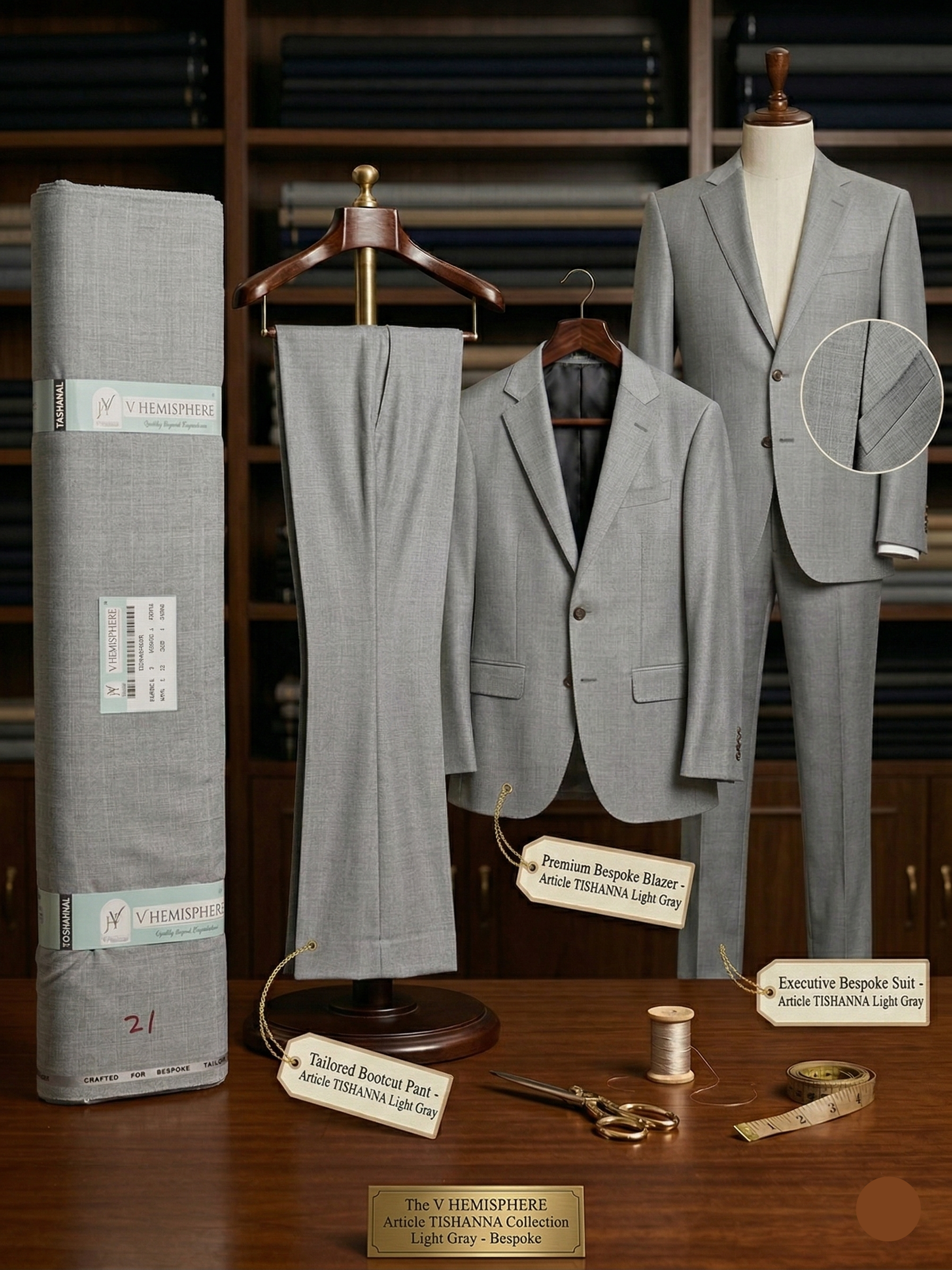 Gray suit displayed on a mannequin with fabric roll and tailoring tools on a wooden surface.