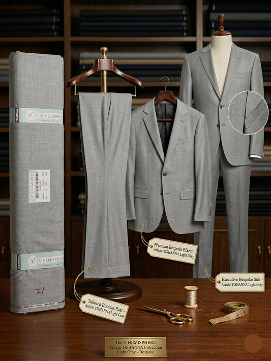 Gray suit displayed on a mannequin with fabric roll and tailoring tools on a wooden surface.