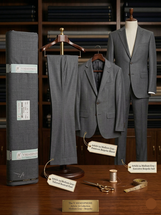 Gray suit on a mannequin with fabric roll and sewing tools on a wooden surface.