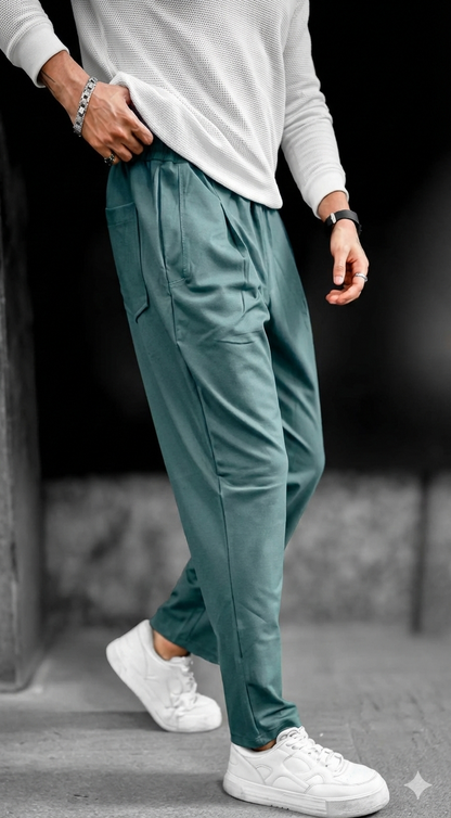 Person wearing teal jogger pants and white sneakers on a blurred background